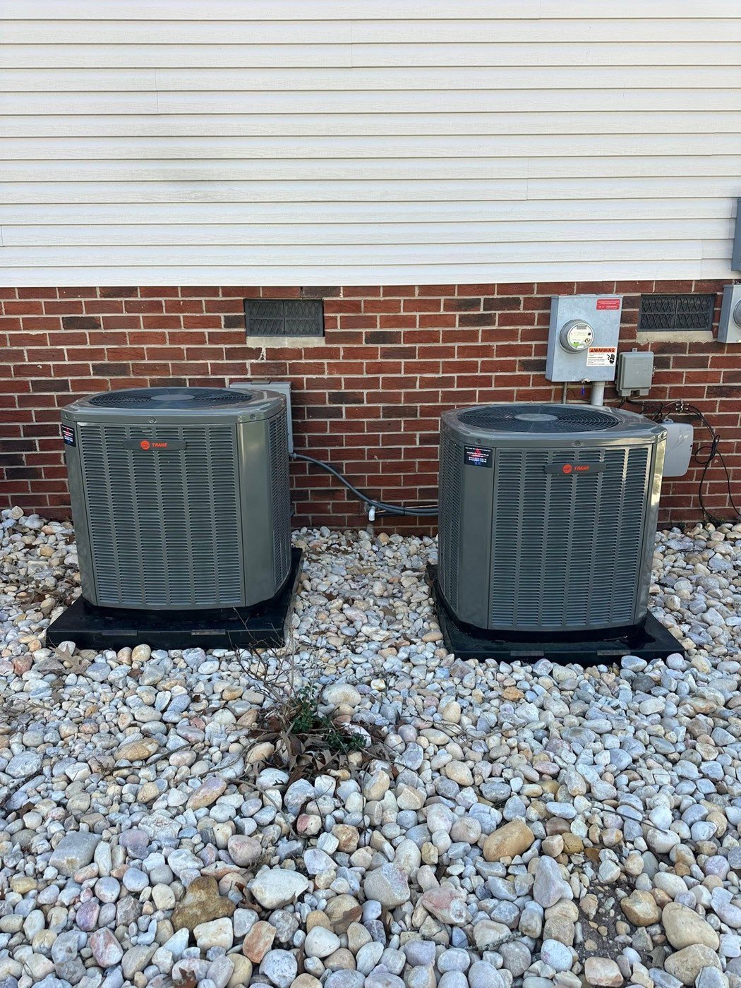 Two new Trane air conditioning condenser units installed outside a home