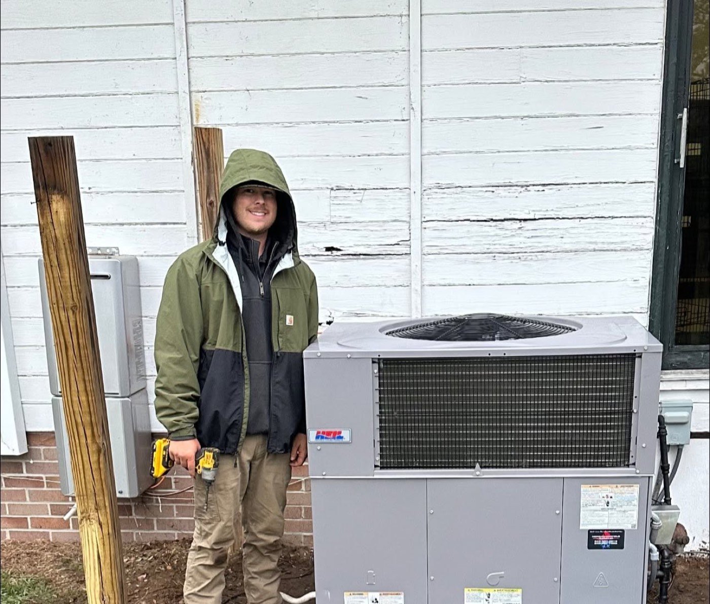 Barfield's technician beside a newly installed Heil heating and cooling unit