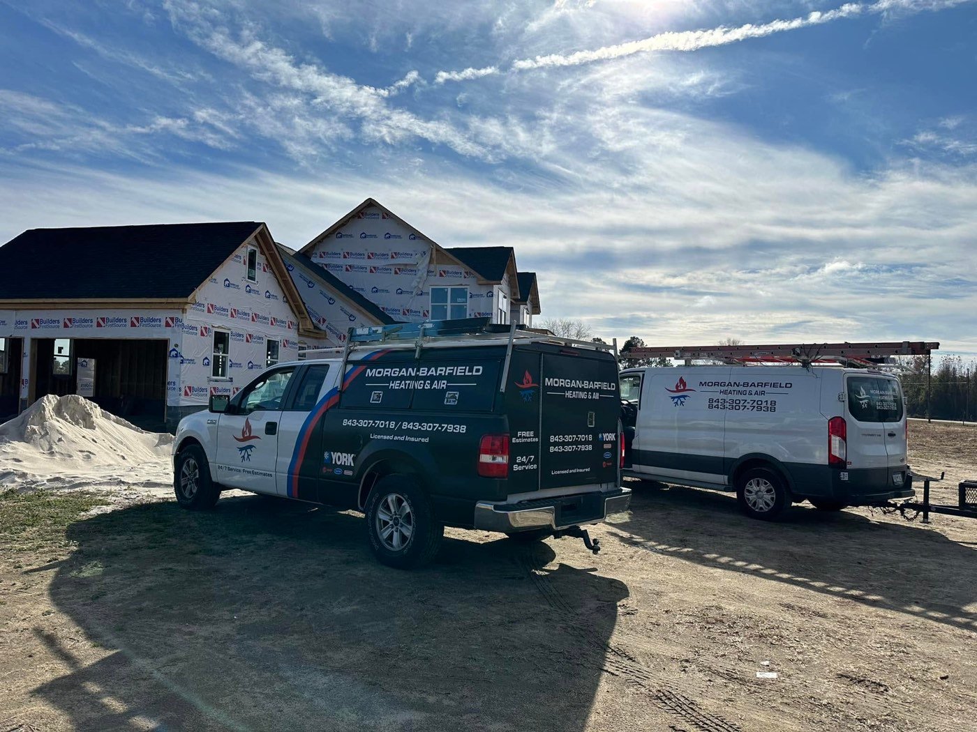 Barfield's Heating & Air service trucks parked at a residential job site under a wide South Carolina sky